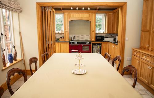a kitchen with a long table with chairs in it at Mere Brook House in Wirral