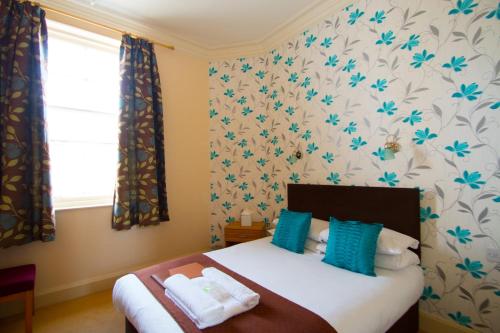a bedroom with a bed with blue and white wallpaper at Royal Mackintosh Hotel in Dunbar