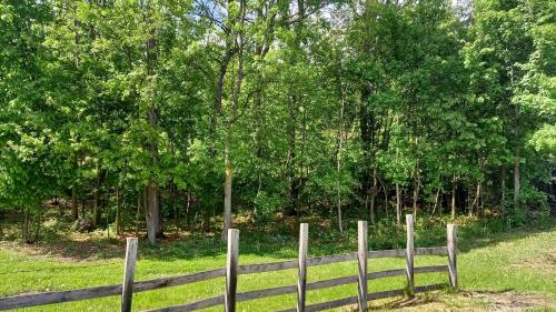 a wooden fence in a field with trees at Šumska čarolija in Kosjerić