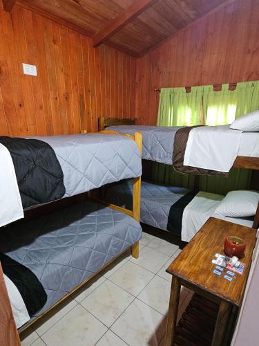 a room with three bunk beds and a table at CABAÑAS PARAISO in Puerto Iguazú