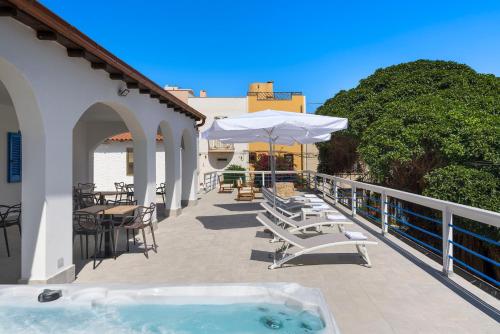 a hot tub on a patio with chairs and umbrellas at DipintodiBlu Charming House in Lampedusa