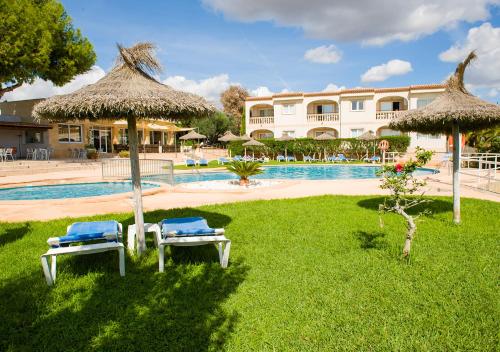 een resort met 2 stoelen en een zwembad bij Apartamentos Sol Romántica by DOT Suites in Cala Romantica
