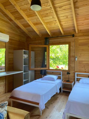 two beds in a room with wooden ceilings and windows at İnlice Ünzile Bungalow İNLİCE KAMP in Fethiye