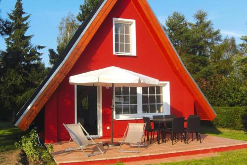 czerwony dom ze stołem i krzesłami przed nim w obiekcie Ferienhaus Chrissi, Rankwitz, Quilitz w mieście Quilitz