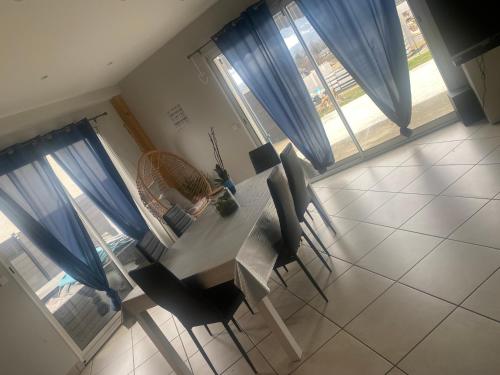 une table à manger et des chaises avec des rideaux bleus dans l'établissement Maison à la campagne 8 personnes, à Sainte-Hélène-du-Lac