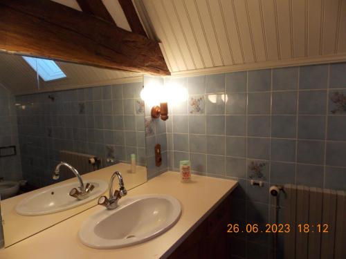 a bathroom with two sinks and a blue tile wall at La Bergeronnette 