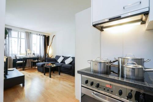 a kitchen and a living room with two pots on a stove at 2 room suite in the heart of Zurich with own washing in Zurich