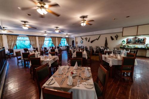 a dining room with white tables and chairs at Gooderson Drakensberg Gardens Golf & Spa Resort in Drakensberg Garden