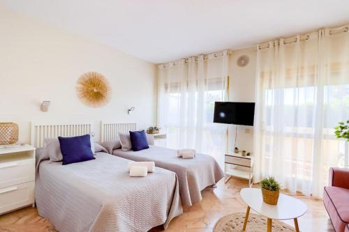 2 camas en una habitación blanca con almohadas azules en OleHolidays 1106 Romana Playa primera línea playa, en Marbella