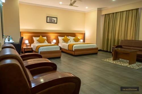 a hotel room with two beds and a couch at Hotel The Black Stone in Bengaluru
