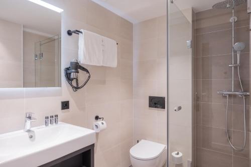 a bathroom with a shower and a toilet and a sink at Boutique Hotel Corona in The Hague