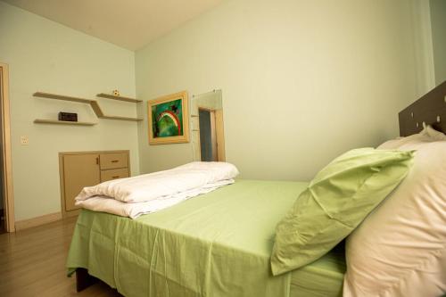 een slaapkamer met een bed met een groene sprei bij Apto com otima localizacao e WiFi em Guarapuava PR in Guarapuava