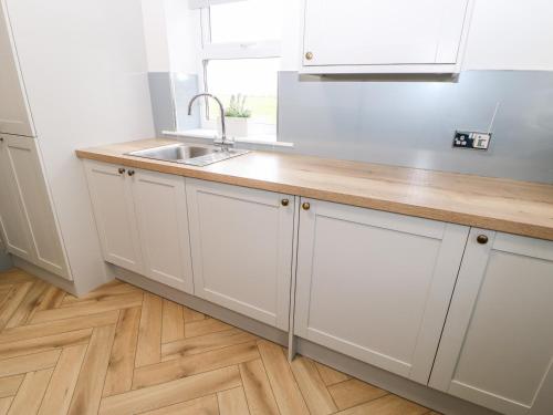 a kitchen with white cabinets and a sink at Forestside View in Bishop Auckland