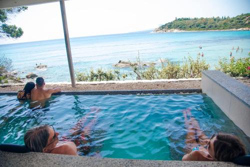 a group of people in a swimming pool overlooking the ocean at Hotel La Bitta - Bovis Hotels in Àrbatax