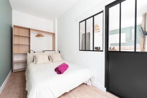 une chambre avec un lit blanc et une grande fenêtre dans l'établissement Le Stalingrad - T2 Moderne - à 2 pas de la Gare, à Toulouse