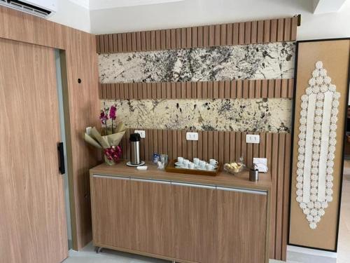 a lobby with a reception desk with flowers on the wall at HOTEL RECANTO DOS IPÊS (UNIDADE 2) in Frutal