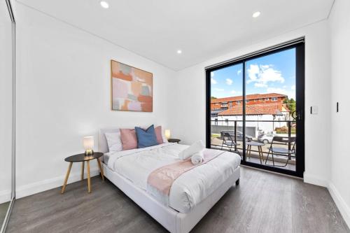 a white bedroom with a bed and a large window at modern 3 bedroom townhous in Ashfield in Sydney