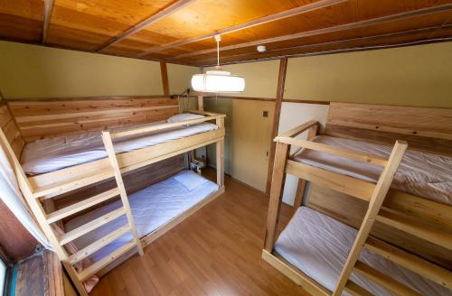 a room with three bunk beds in it at おせっかいゲストハウス 昭和の寅や in Chikuma