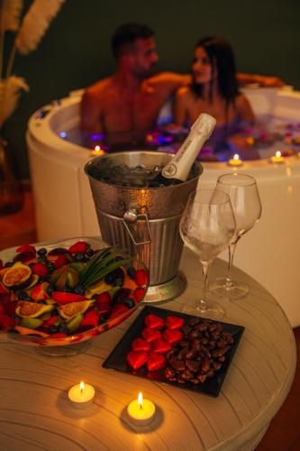 a table with a plate of food and a bathtub with a man in at Hotel La Bitta - Bovis Hotels in Àrbatax