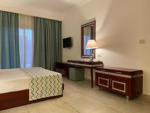 ein Hotelzimmer mit einem Bett, einem Schreibtisch und einem Spiegel in der Unterkunft Oyster Bay Marsa Alam (unit I6-13) in Abu Dabab