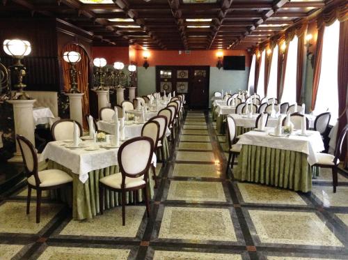 una sala da pranzo con tavoli e sedie bianchi di Garni Hotel a Minsk