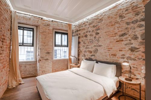 a bedroom with a white bed and a brick wall at Homie Suites - One Bedroom Apartment in Galata in Istanbul