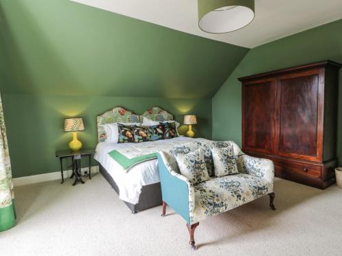 a green bedroom with a bed and a chair at Auchenvhin - Rockcliffe in Dalbeattie