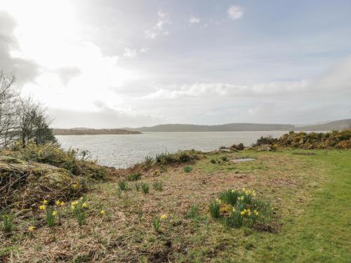 a grassy field next to a body of water at Auchenvhin - Rockcliffe in Dalbeattie