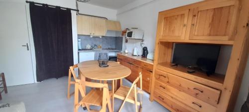 une cuisine avec une table en bois et une cuisine avec une télévision dans l'établissement Le Solarium, aux Angles