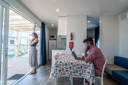 a man and a woman sitting at a table with a laptop at Camping Village Garden Paradiso in Cavallino-Treporti