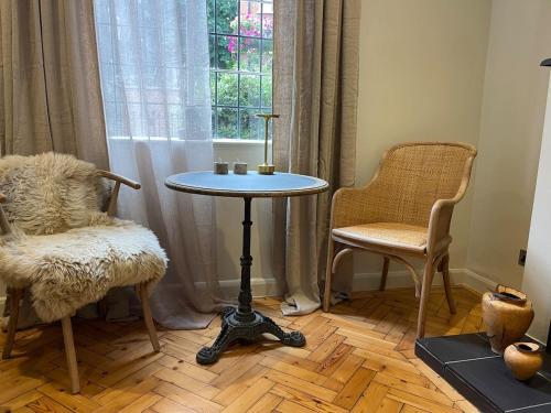 einen Tisch und zwei Stühle in einem Zimmer mit Fenster in der Unterkunft Luxury London English Charm in London