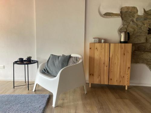 a living room with a white chair and a wooden cabinet at house in the medieval village in Apricale