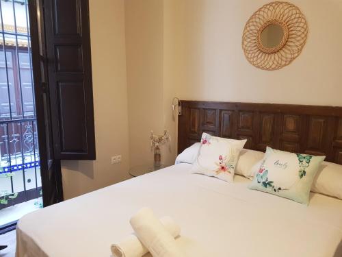 a bedroom with a bed with white sheets and pillows at Apartamentos Alhambra Granada 3000 in Granada