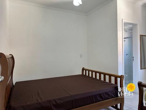 a bedroom with a bed in a white wall at Thel Ubatuba - Apto 27/A, Monte Carlo - Praia Grande in Ubatuba