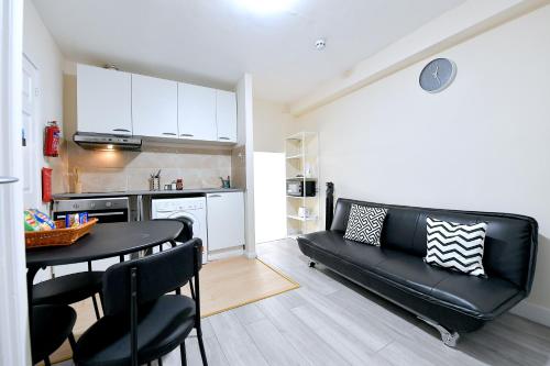a living room with a table and a black leather couch at City Apartments near Seven Sisters in London