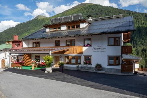ein großes weißes Gebäude mit einem Berg im Hintergrund in der Unterkunft Haus Praxmarer in Sankt Anton am Arlberg