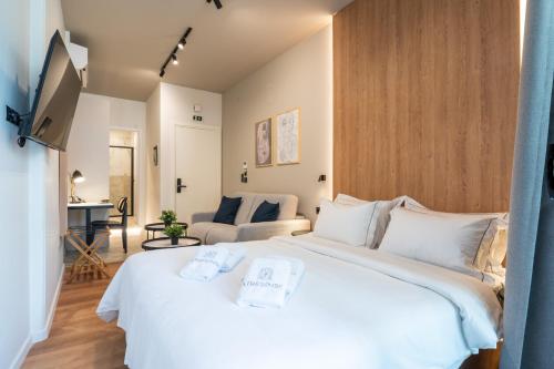 - une chambre avec un grand lit blanc et un canapé dans l'établissement Athesense Suites, à Athènes