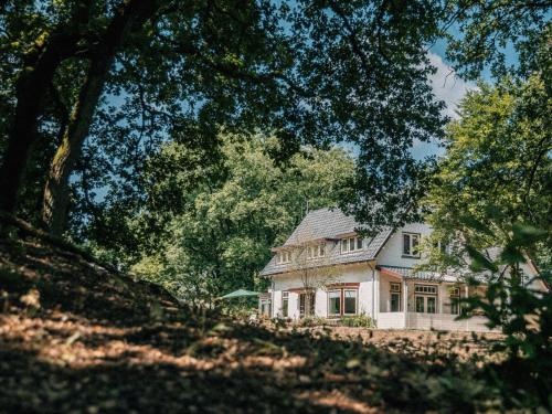 une grande maison blanche avec des arbres devant elle dans l'établissement de Wever Lodge, à Otterlo