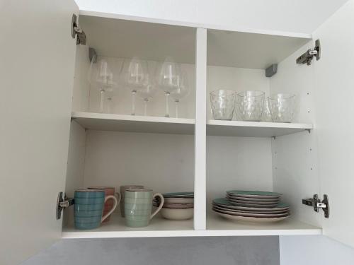 a white cabinet with plates and cups and bowls at Appartement Donauwelle 1 in Passau