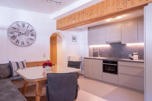 eine Küche mit einem Tisch und einer Uhr an der Wand in der Unterkunft Haus Praxmarer in Sankt Anton am Arlberg
