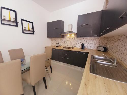 a kitchen with a sink and a table with chairs at Luxury Penthouse with private pool in Tas-Samra