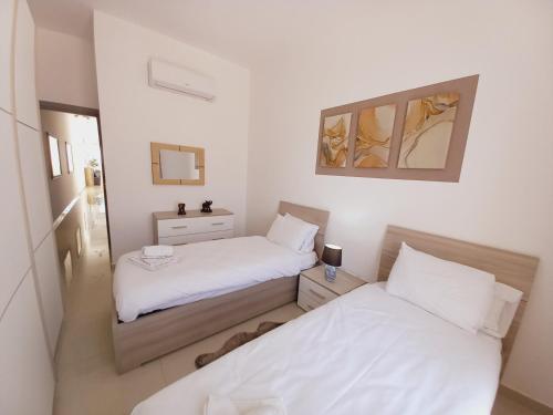 two beds in a small room with white sheets at Luxury Penthouse with private pool in Tas-Samra