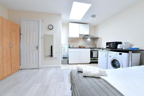 a white room with a bed and a kitchen at City Apartments near Seven Sisters in London