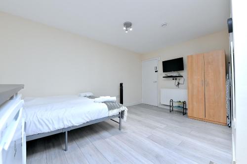 a bedroom with a bed and a flat screen tv at City Apartments near Seven Sisters in London