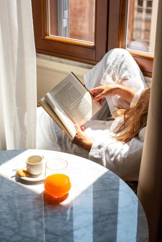 a woman sitting in a chair reading a book at Sentho Roma in Rome