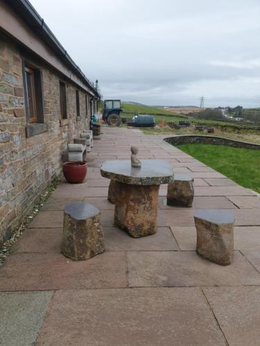 a stone patio with a table and some rocks at The Coach House in Baxenden