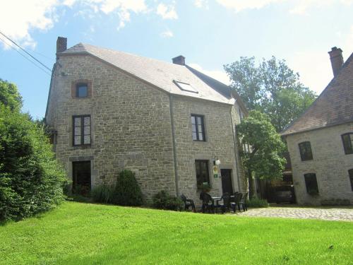 an old stone house with two chairs in the yard at Lovely Holiday Home in Treignes with Garden in Treignes