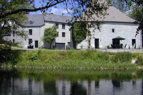 a large white building next to a body of water at Lovely Holiday Home in Treignes with Garden in Treignes