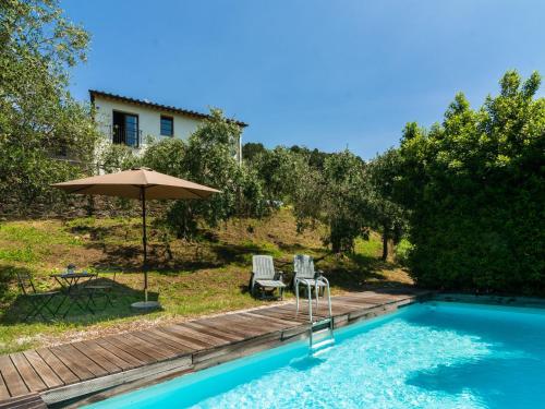 UzzanoにあるIdyllic Holiday Home in Pescia with Swimming Poolの家の隣に椅子2脚とパラソル1本付きのプールがあります。
