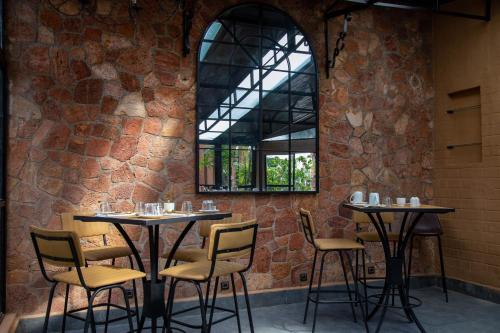 un restaurante con 2 mesas y sillas y una ventana en Le Pavillon de l'Emyrne, en Antananarivo